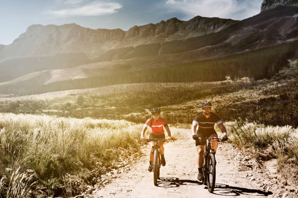 Friends riding bicycles on dirt road by mountains