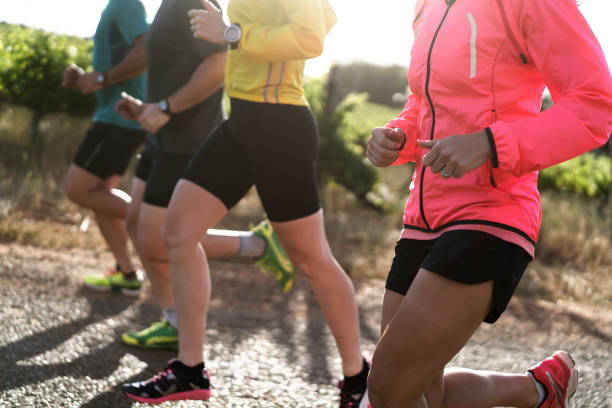 istock Low section of men and women jogging on road 866123714