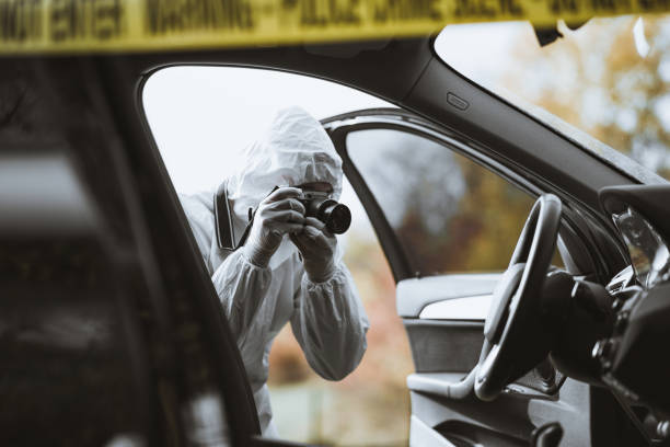 Forensic scientist taking a picture of a car interior A forensic scientist is seen on a crime scene photographing a car interior looking for details. criminal investigation photos stock pictures, royalty-free photos & images