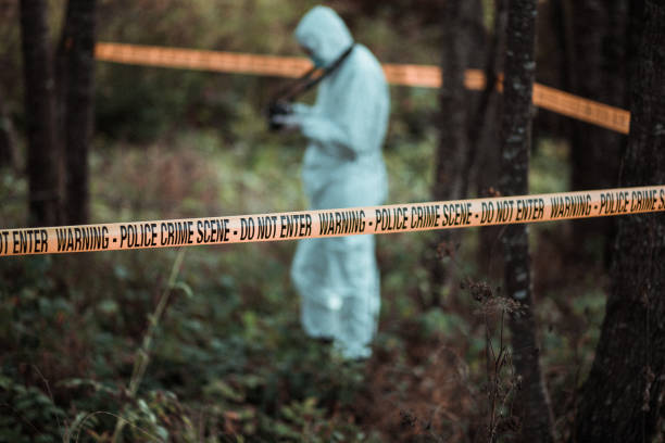 istock Forensic scientist photographing an area that is marked with a cordon tape 866132684