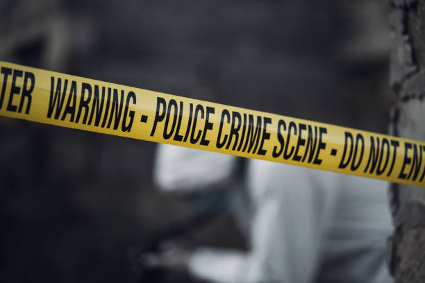 istock Cordon tape with a forensic scientist in the background photographing 866132750