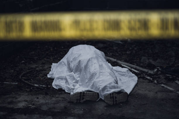 Dead body on the ground behind a cordon tape The dead body is seen lying on the ground behind a cordon tape. dead person photos stock pictures, royalty-free photos & images
