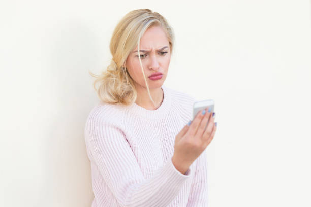istock Angry young woman using phone on blank wall 866155088