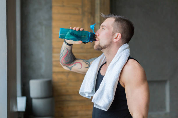 istock Handsome thirsty young man in gym, drinking water from bottle 866162830
