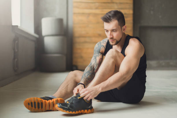 istock Handsome young man lace shoes at gym after training 866163102