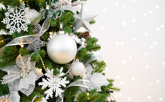 Christmas ball with red bow hanging on Christmas tree branch isolated on white background.