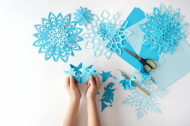 herstellung von schneeflocken aus blauem papier. - snowflake winter blue paper stock-fotos und bilder