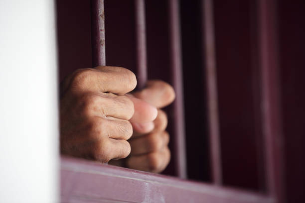 istock hands of prisoner in jail as background. 866186352