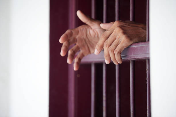 istock hands of prisoner in jail as background. 866186406