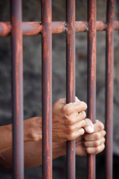 istock hands of prisoner in jail as background. 866186522