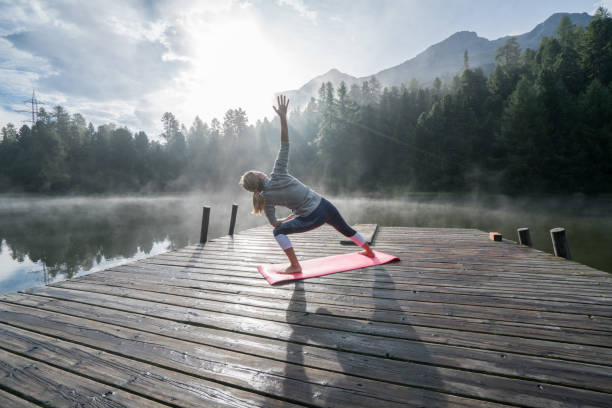 istock Woman practicing yoga poses in nature, lake pier 866200968