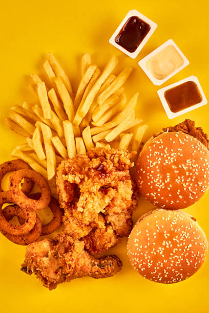 Top view hamburger, french fries and fried chicken on yellow background. Copy space for your text