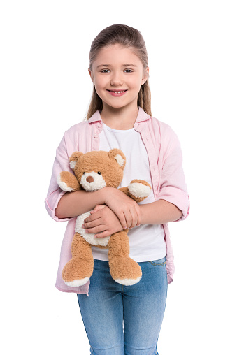 Half-length shot of a smiling little girl holding a teddy bear and looking at camera