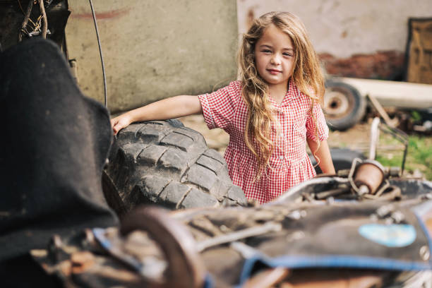 Small girl standing next to an old tractor in the ghetto