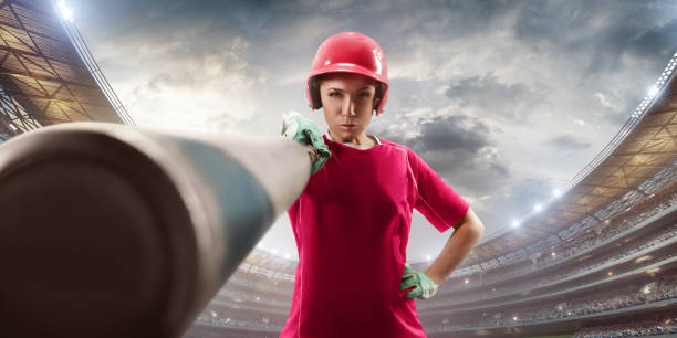 Softball female player on a professional arena Softball female player on a professional arena. Beautiful athlete with sport bat in unbranded uniform on big arena. The player shows a bat in the camera. softball pitcher stock pictures, royalty-free photos & images