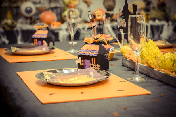 istock Reception table with a black tablecloth and decorations for halloween parties, a small cardboard house, glasses and cardboard plates 866232454
