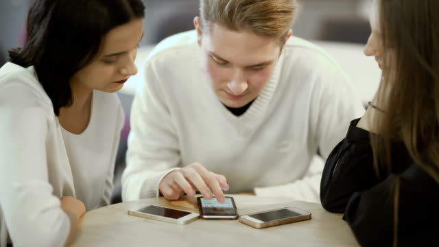 Three friends looks on the screen of smartphone
