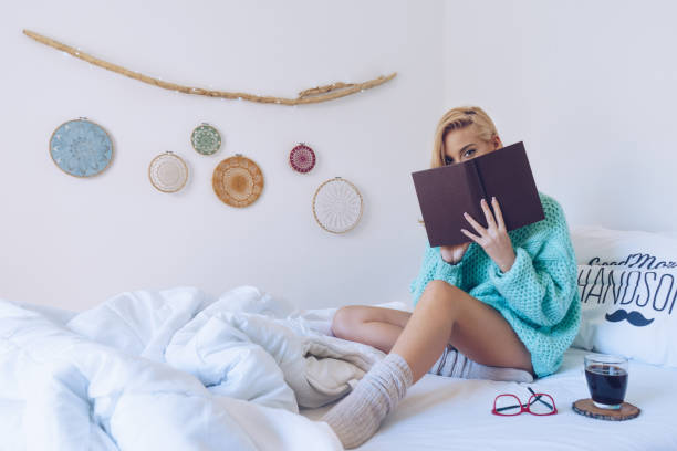 istock Young woman sitting in bed while reading a book 866237462