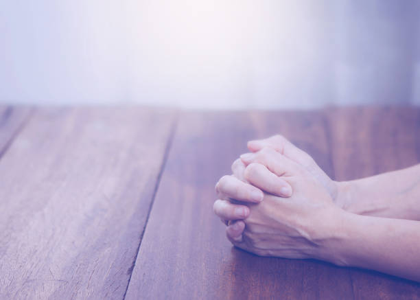 istock man hands and pray on wooden table 866244160