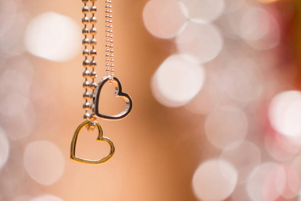 dwa wisiorki serca z naszyjnikiem wyizolowanym na miękkim świecącym tle - necklace jewelry heart shape gold zdjęcia i obrazy z banku zdjęć