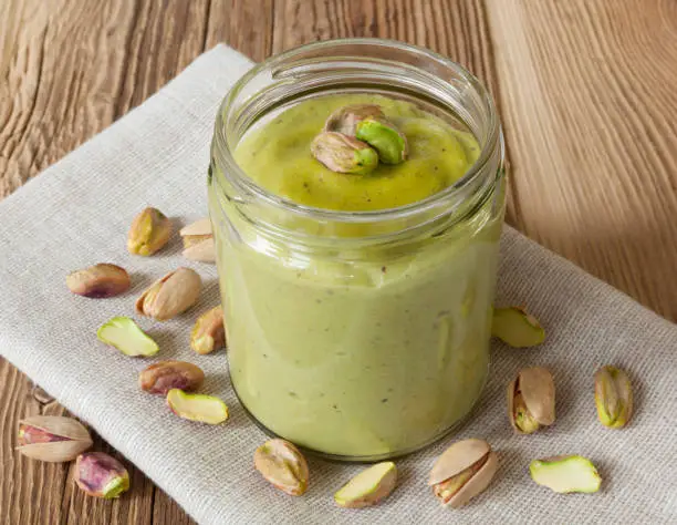 Homemade pistachio butter on wooden table