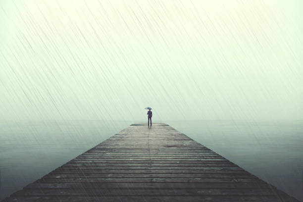 istock Sad man with umbrella on a boardwalk under rain 866264018