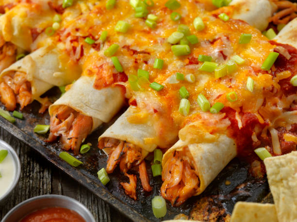 gebackene chicken enchiladas - cheese focus on foreground on top of portion stock-fotos und bilder