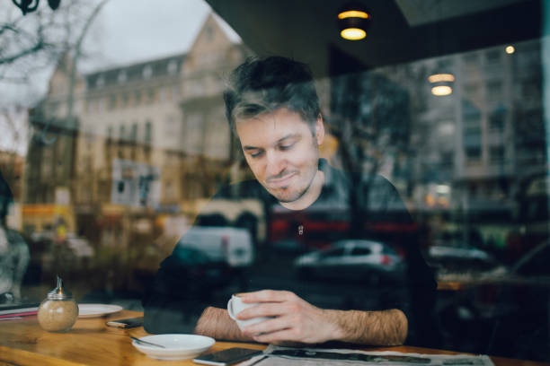 istock Young man relaxing in a cafe in Berlin, reading the newspapers 866275982