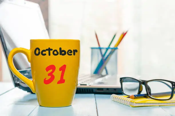 Photo of October 31st. Day 31 of month, calendar on hot coffee cup at translator or interpreter workplace background. Autumn time. Empty space for text