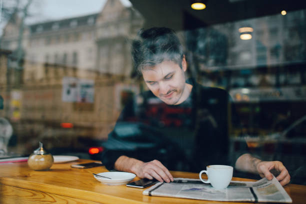istock Young man relaxing in a cafe in Berlin, reading the newspapers 866287544