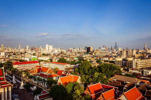 High view on the capital city of Thailand, with red roofs green trees and blue sky on the background