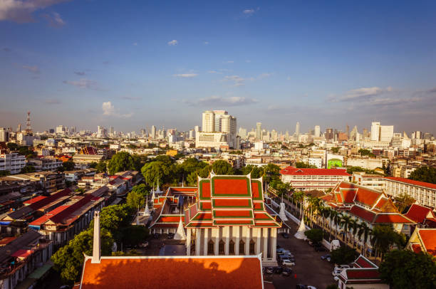 High view on the capital city of Thailand, with red roofs green trees and blue sky on the background