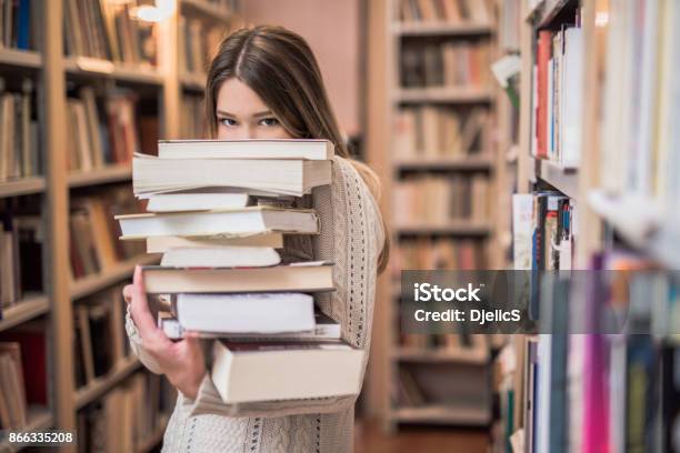 Beautiful Teenage Girl Hiding Behind A Stack Of Books Stock Photo - Download Image Now