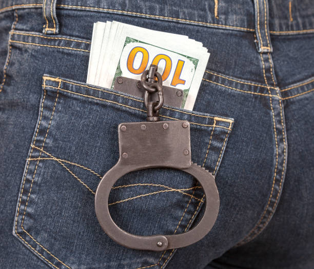 Black metal handcuffs and american currency in back jeans pocket Black metal handcuffs and american currency in back jeans pocket terrorist financing stock pictures, royalty-free photos & images