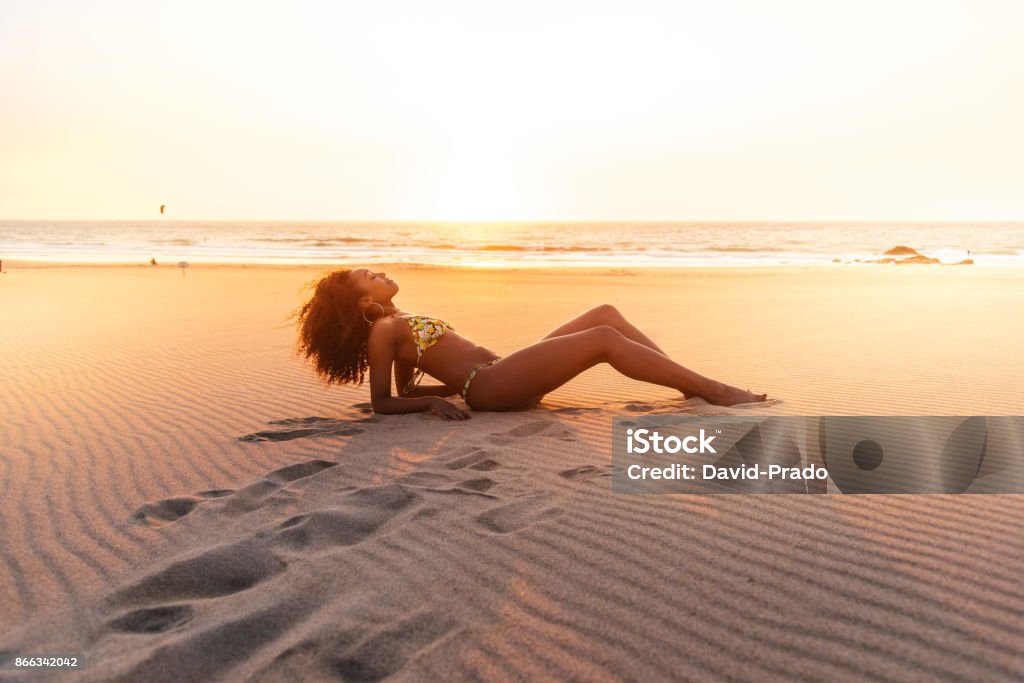 Beautiful young woman posing on the sand at the beach Beach Stock Photo