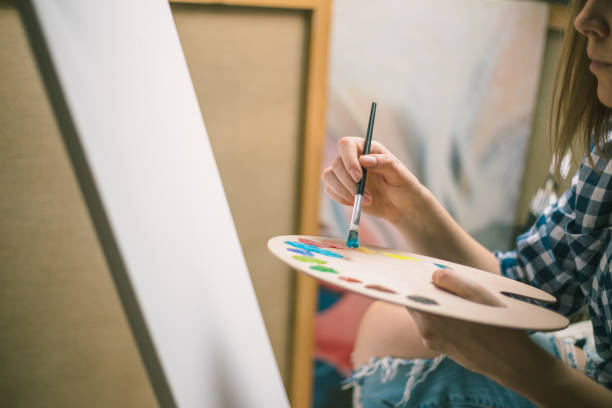 istock Happy young woman paints on canvas 866353902