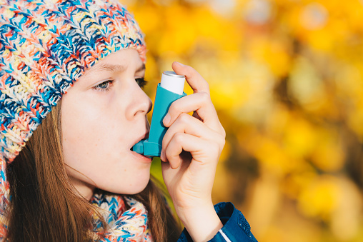 Chica paciente asma la inhalación de medicamentos para tratar la dificultad para respirar y sibilancias en un parque photo