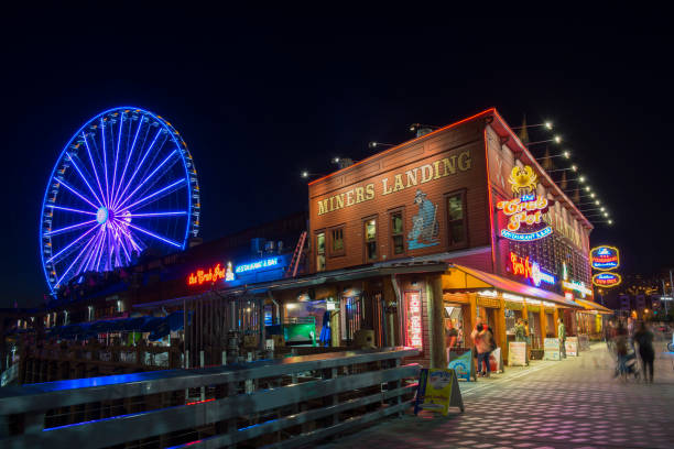 Tourists at Miners Landing in Seattle Seattle, USA - September 28, 2017. Tourists dining or buying food at or walking past Miners Landing food court at Pier 57 with view of Seattle Great Wheel on Alaskan Way in waterfront area of downtown Seattle, Washington State. seattle ferris wheel stock pictures, royalty-free photos & images