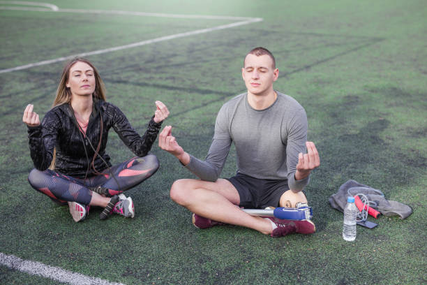 Couple meditating 28 yrs old couple is meditating outdoors. They are trying to concentrate and relax their body Mental and Emotional Benefits sports stock pictures, royalty-free photos & images