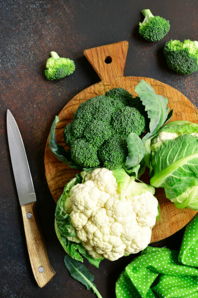 Raw broccoli and cauliflower on a oak cutting board