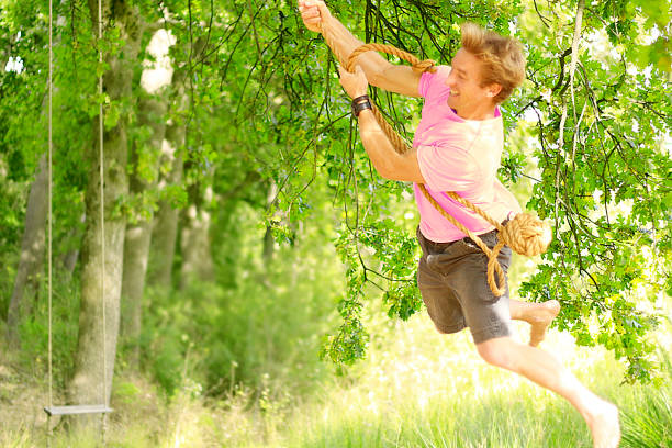 istock People outdoors swinging man trees happy fun playing park sunny 866374484
