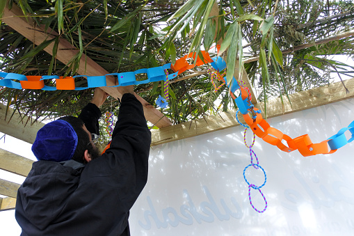 Jewish Orthodox man decorating a Sukkah on sukkot Feast of Tabernacles, Feast of the Ingathering or Feast of booths. Copy space