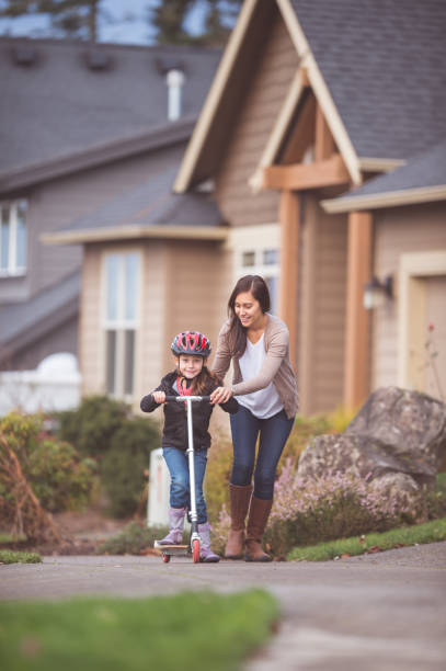 istock Mom teaches daughter how to ride a scooter 866386332