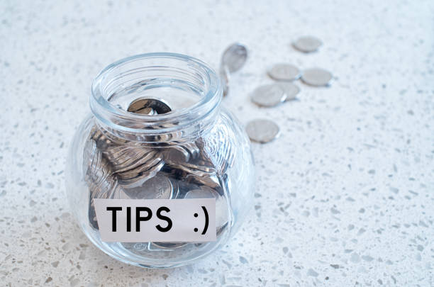 istock Glass jar with many coins and tips word  over a marble counter top 866392852