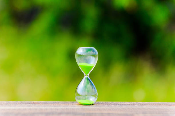 istock hourglass and green blur background 866393050