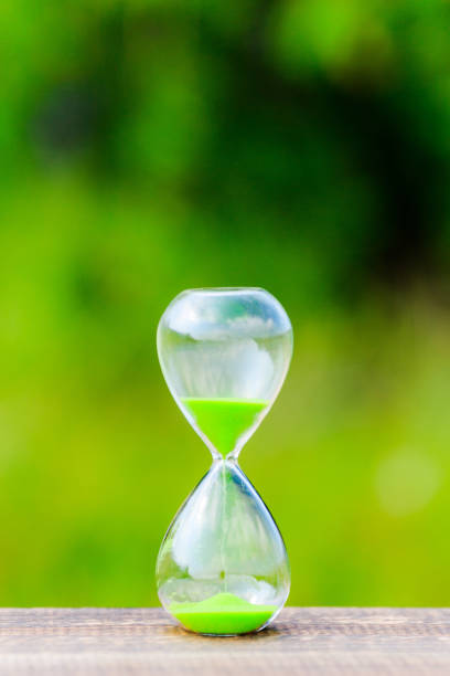 istock hourglass and green blur background 866393288