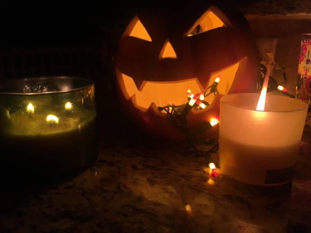 istock Spooky Evil Scary Jack O Lantern Halloween Pumpkin in the Night Dark Black Background with Candles 866393302