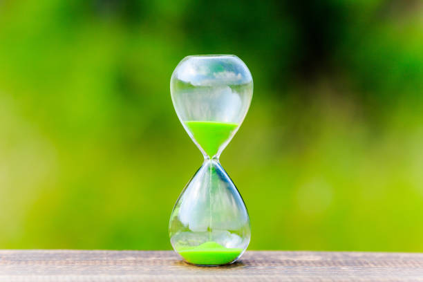 istock hourglass and green blur background 866393428