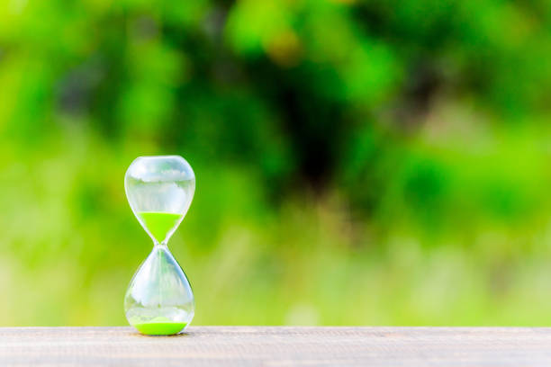 istock hourglass and green blur background 866394058