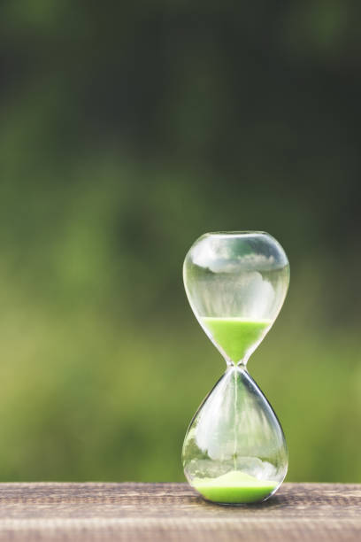 istock hourglass and green blur background 866396646